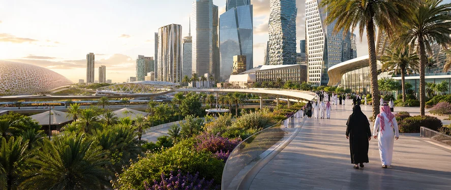 People walking a landscaped promenade beside modern skyscrapers in a Saudi Arabia smart city