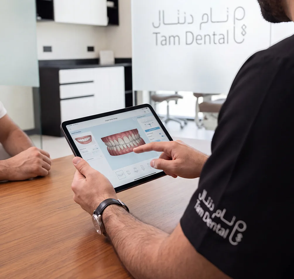 Dentist showing a patient a digital smile treatment plan on a tablet at Tam Dental in Jeddah