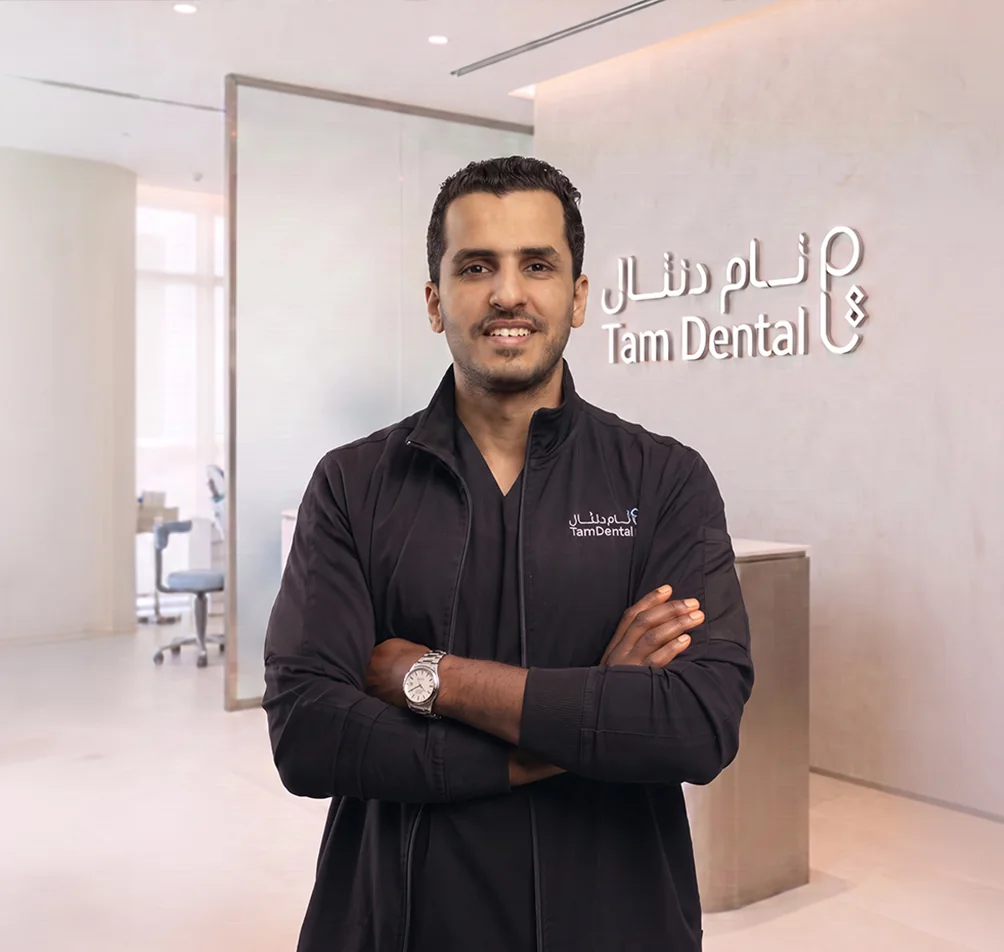 Dr. Ahmed Alghamdi standing beside the Tam Dental reception sign in Jeddah