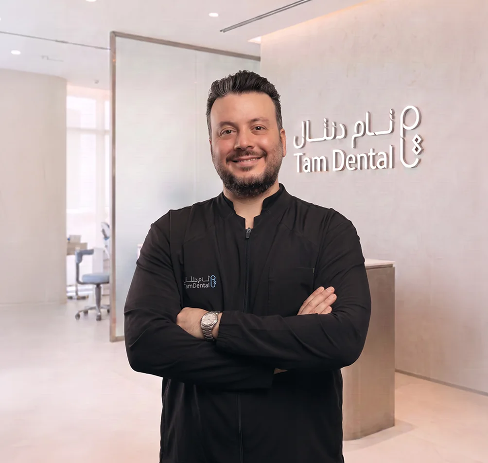 Dr. Badr Othman standing beside the Tam Dental reception sign in Jeddah