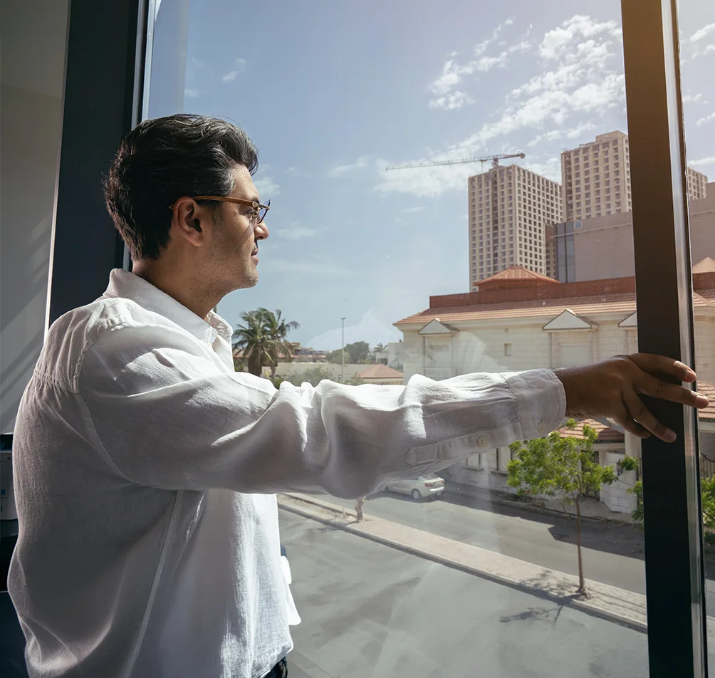 Dr. Rayan Bahabri, endodontist at Tam Dental, standing by the office window in Jeddah