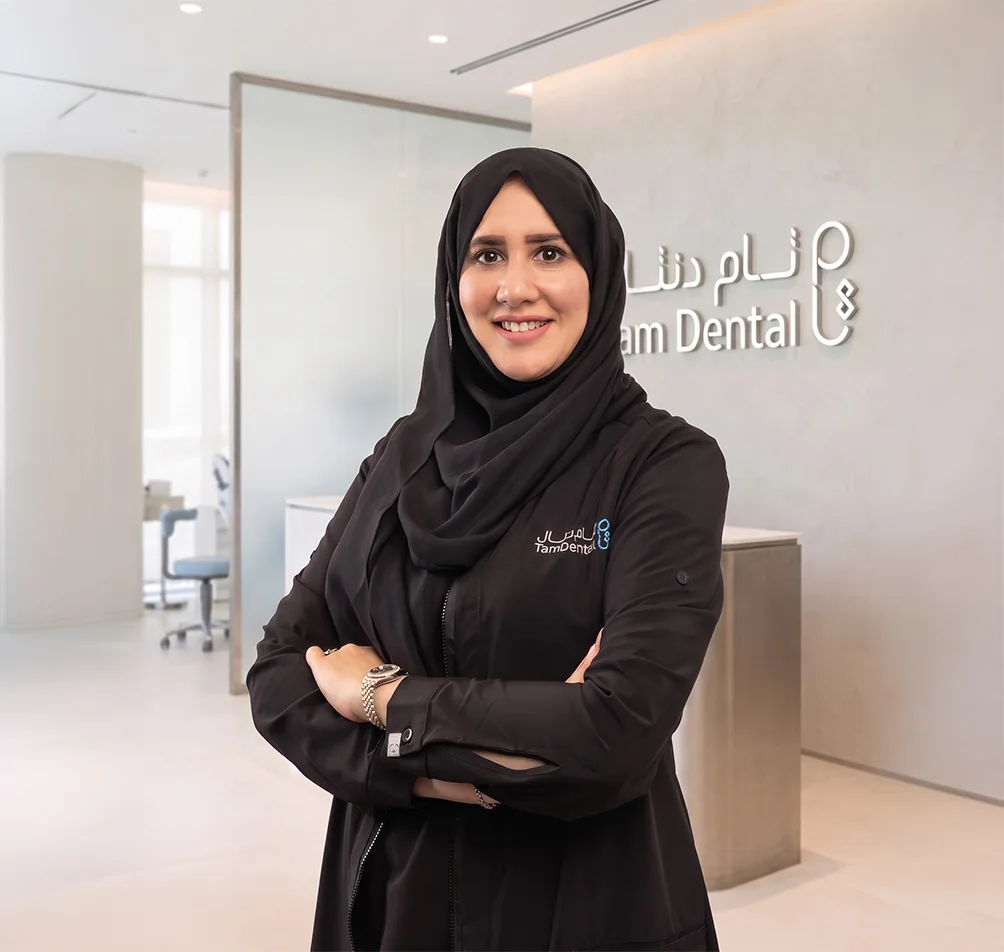 Dr. Salma Ghoneim standing beside the Tam Dental reception sign in Jeddah