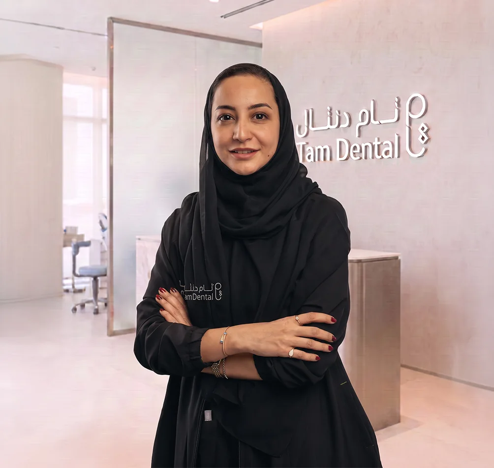 Dr. Shatha Alshali standing beside the Tam Dental reception sign in Jeddah
