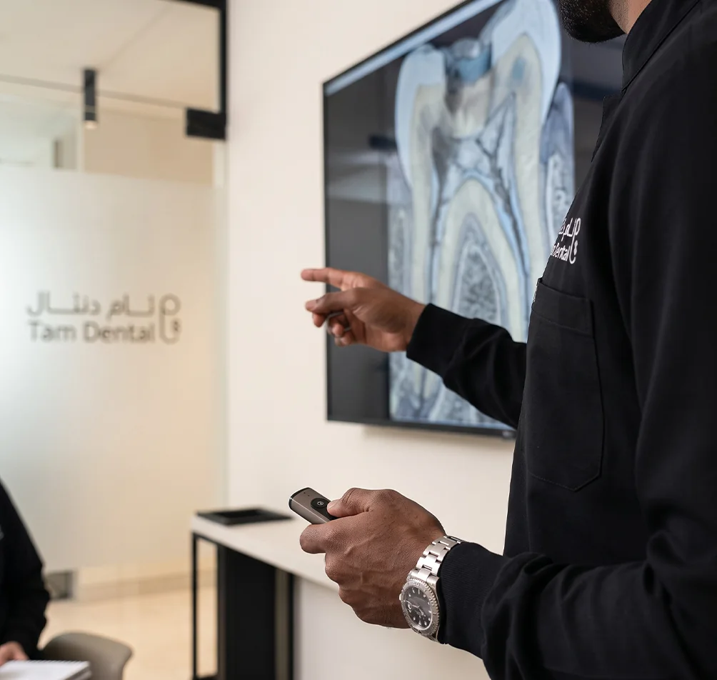 Endodontist explaining tooth and root canal anatomy on a screen to a patient at Tam Dental in Jeddah