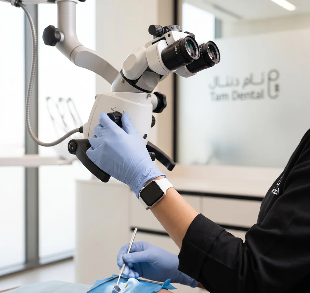 Endodontist using a dental operating microscope during root canal treatment at Tam Dental in Jeddah