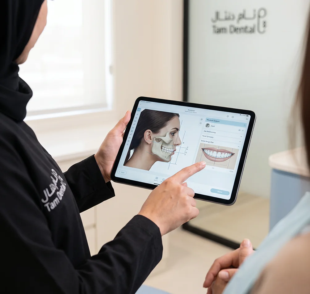 Orthodontist showing a patient a digital smile and facial analysis on a tablet at Tam Dental in Jeddah