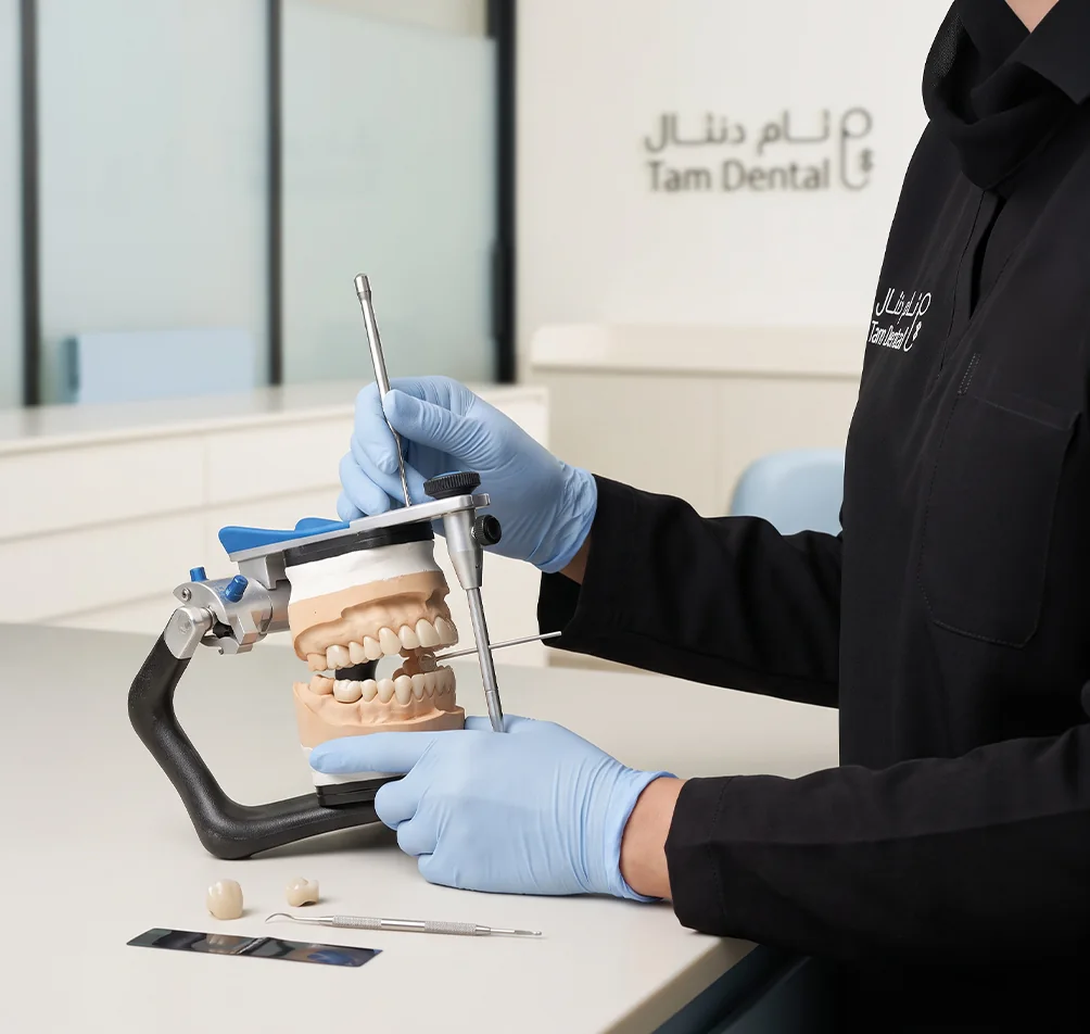 Prosthodontist working on a dental model mounted on an articulator at Tam Dental in Jeddah