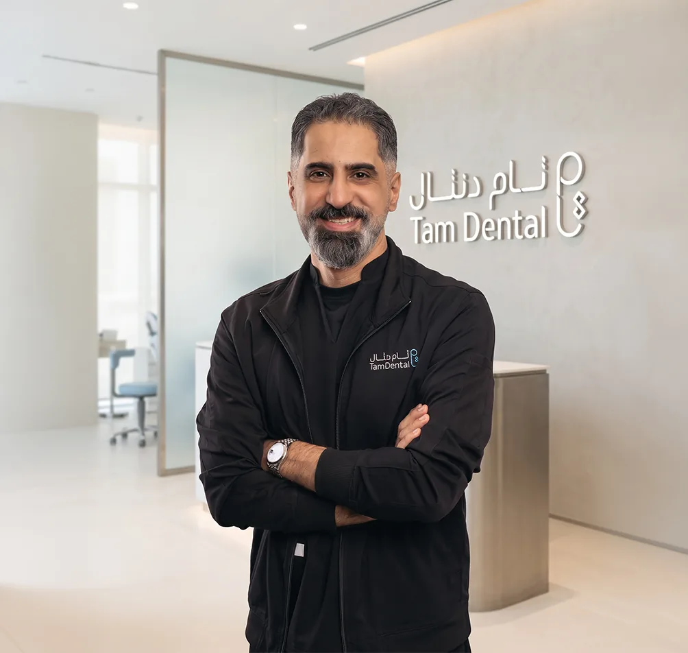 Tam Dental dentist standing beside the clinic reception sign in Jeddah
