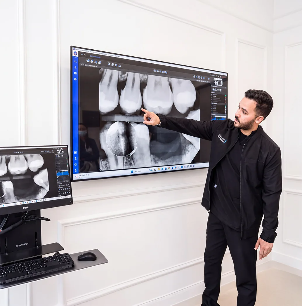 Dentist reviewing dental X-rays on a large screen while planning veneers and crowns