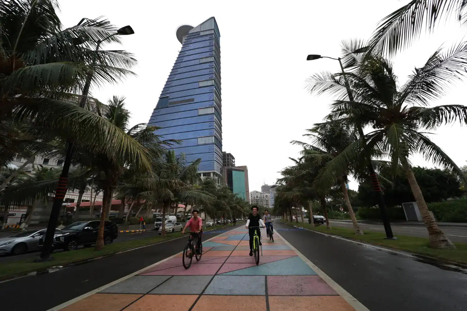 Cyclists on the palm-lined Jeddah Corniche cycling path beside the Red Sea, Saudi Arabia